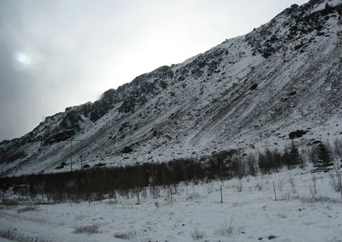 A photo of an apocalyptic looking midday sun over black and white hills in Iceland.