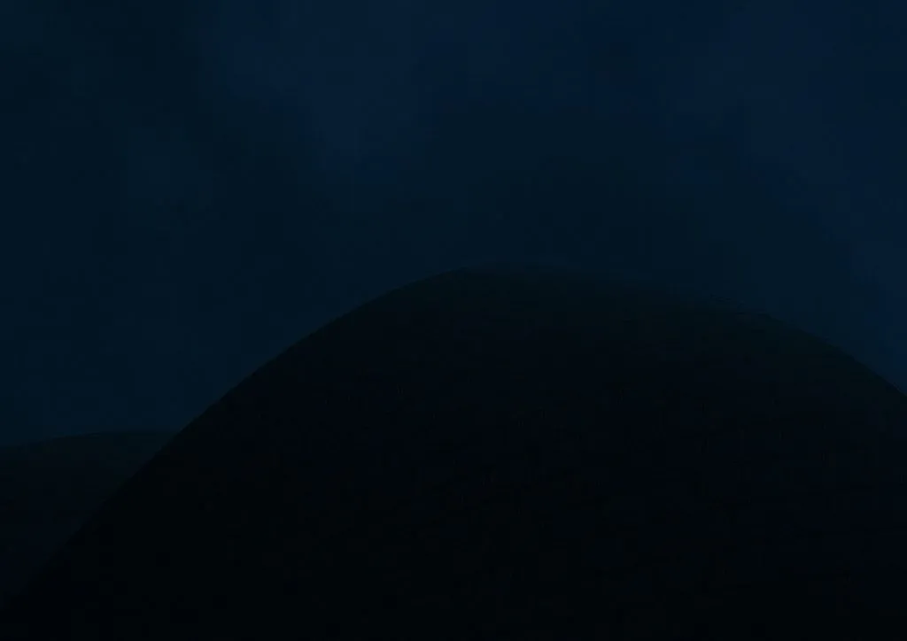 A low contrast night photo of the opera house where the main colours are a deep navy sky and black silhouetted shells.  