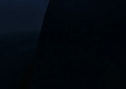A low contrast night photo of the opera house where the main colours are a deep navy sky and black silhouetted shells.