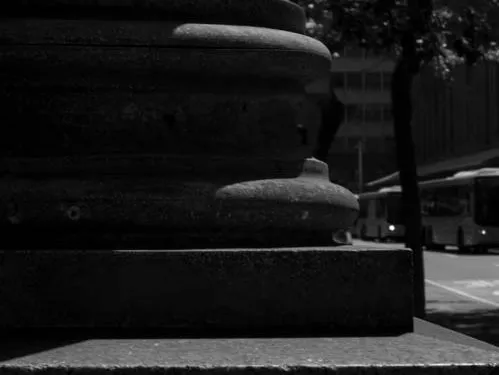 A black and white photo of a classical ionic column in deep shadow with a sign for Red Eye Records in the background.